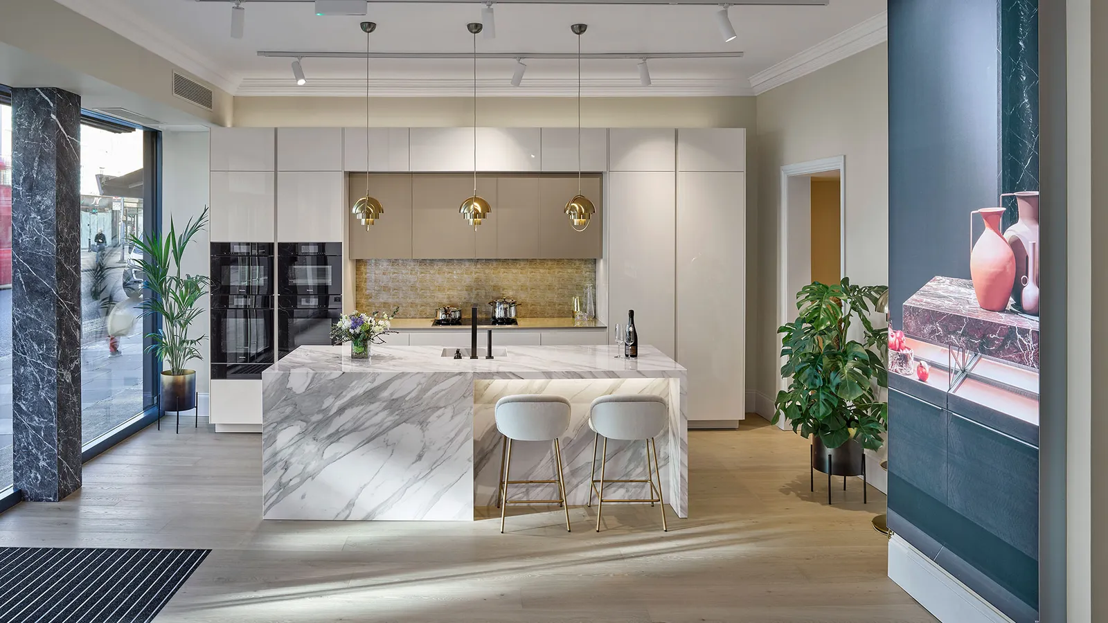 Großzügige Showroom-Küche mit heller Marmorinsel und goldenen Lichtakzenten