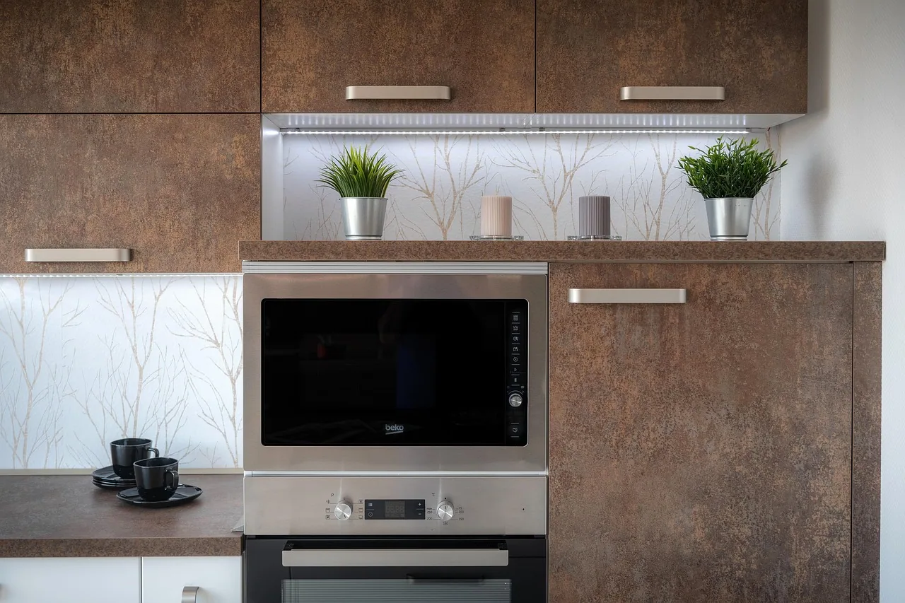 Eine moderne Küche mit braun gemaserten Hochschrankfronten, einem integrierten Mikrowellengerät und einem Backofen darunter