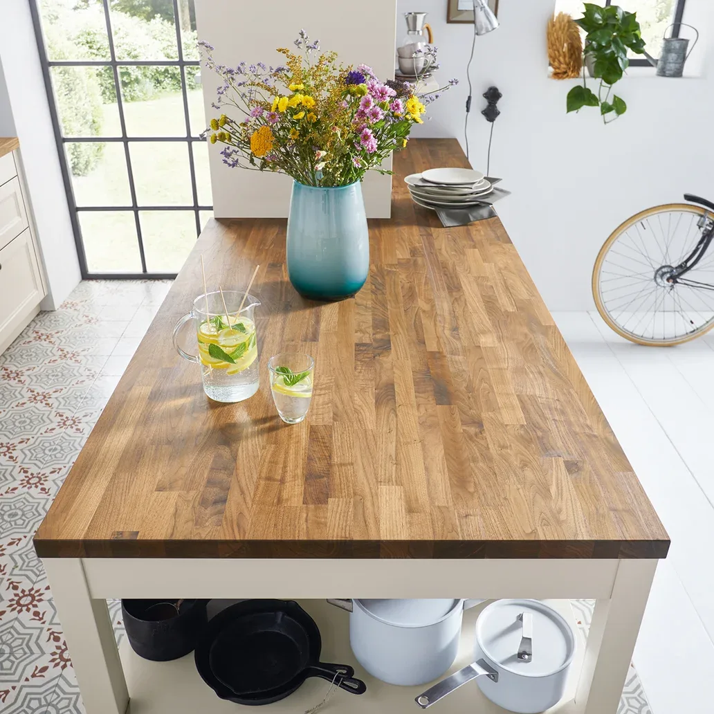 Schüller Massivholz-Arbeitsplatte aus Nussbaum, Nahaufnahme Maserung mit Krug und Glas